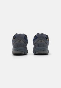 Two pairs of dark blue and grey sneakers with mesh and suede materials, featuring perforated detailing and a cushioned sole design.