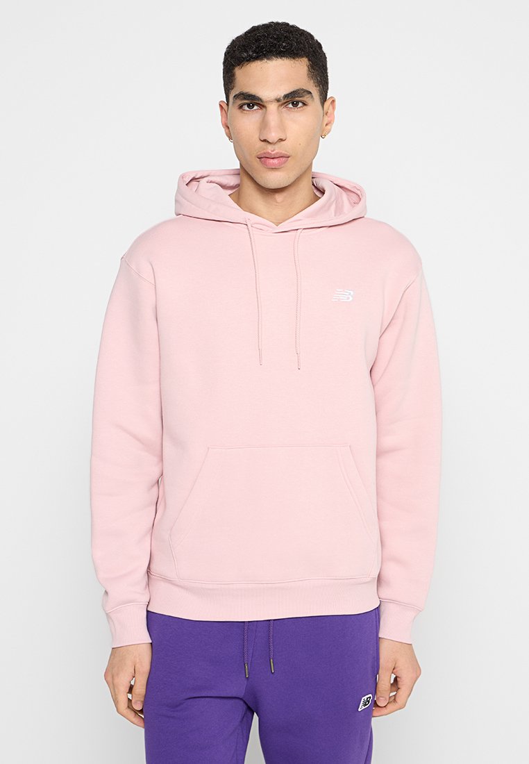 Sweatshirt à capuche rose clair en matériau doux, avec une poche kangourou à l'avant et un logo blanc sur la poitrine gauche.