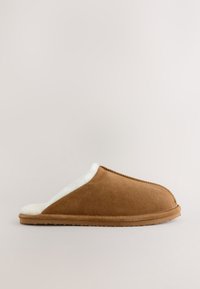 Brązowy zamszowy kapcie z miękkim białym futerkiem w środku, zamkniętym tyłem i teksturowaną gumową podeszwą. Posiada staranne przeszycia wzdłuż krawędzi.