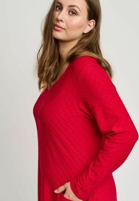 Röd långärmad klänning med ett texturerat mönster, rund halsringning och två sidofickor. Mjukt tyg och avslappnad passform, lämplig för avslappnad användning.