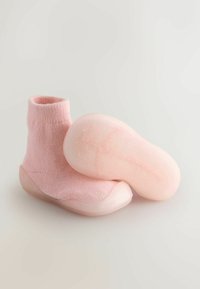 Różowe dziergane buciki z miękką, elastyczną gumową podeszwą. Wierzch to teksturowana dzianina, a podeszwa ma wzorzysty spód zapewniający dobrą przyczepność.