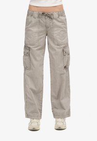 Lässige graue Cargo-Hosen mit großen vorderen und seitlichen Taschen, elastischem Bund mit Kordelzug, getragen mit weißen Turnschuhen.