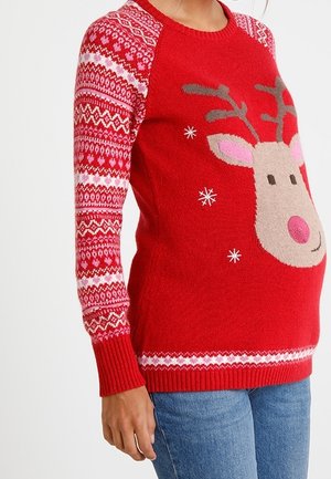 Czerwony sweter świąteczny z wizerunkiem renifera, płatkami śniegu i wzorzystymi rękawami, noszony przez osobę w niebieskich dżinsach.