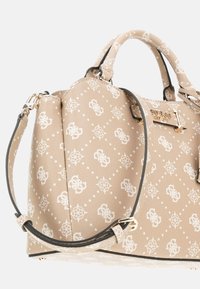 Borsa Guess beige con motivo logo bianco, hardware dorato, manici corti e una tracolla regolabile su uno sfondo semplice.