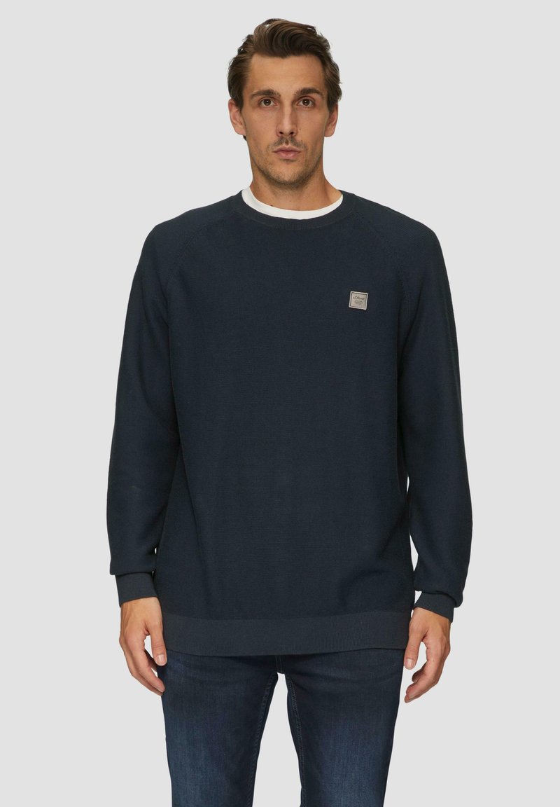 Dunkelblauer Pullover aus strukturiertem Stoff. Er hat einen Rundhalsausschnitt, gerippte Bündchen und Saum sowie ein kleines Logo-Patch auf der Brust.