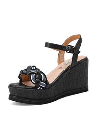 Sandalo con zeppa piattaforma nera con base in tessuto denim. Presenta un accento colorato intrecciato sulla cinghia e una fibbia regolabile alla caviglia.