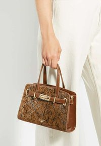 Brown handbag featuring a textured fur-like front, smooth leather sides, gold hardware, dual handles, and a zip closure.