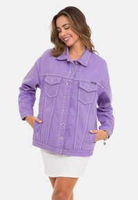 Lila Jeansjacke mit silberner Hardware, zwei Brusttaschen und kontrastierenden Nähten. Sie verfügt über einen kragenlosen Halsauschnitt und einen lässigen Schnitt.