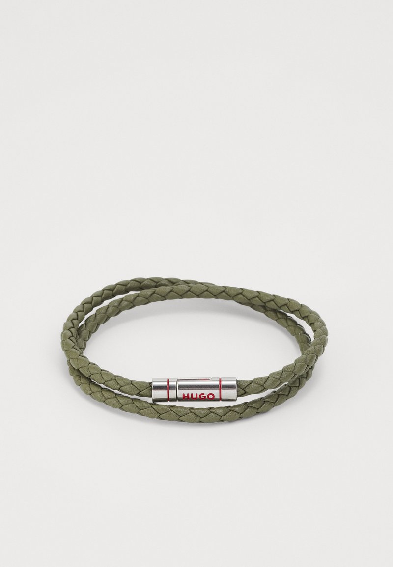 Bracciale intrecciato in pelle verde oliva con chiusura magnetica in argento e il logo rosso "HUGO". Doppi giri, texture liscia.