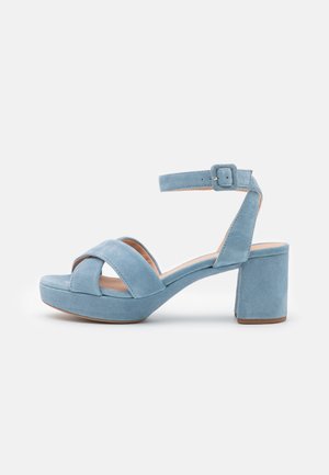 Light blue suede platform sandals with crossed straps, chunky block heel, and adjustable ankle strap. Smooth texture, simple design.