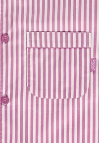 Primer plano de una camisa con rayas verticales rosas y blancas, con un bolsillo frontal y dos botones rosas en el lado izquierdo.