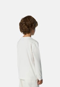 Camicia bianca a maniche lunghe realizzata in cotone morbido, con scollo rotondo e orlo dritto. Tessuto leggermente strutturato senza motivi.