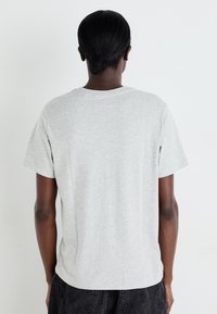 Grå kortærmet t-shirt lavet af blød bomuld. Løs pasform med rund hals og en glat, ensfarvet tekstur. Ingen synlige mønstre eller detaljer.