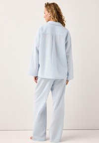 Blå och vitrandig pyjamasset, med texturerad tyg, långa ärmar och löst sittande byxor med en avslappnad siluett.