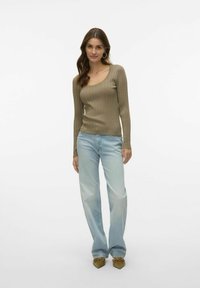 Olivgrön ribbade långärmade topp med fyrkantig halsringning, parat med ljusblå vida jeans och spetsiga klackar med scalloped-kant.