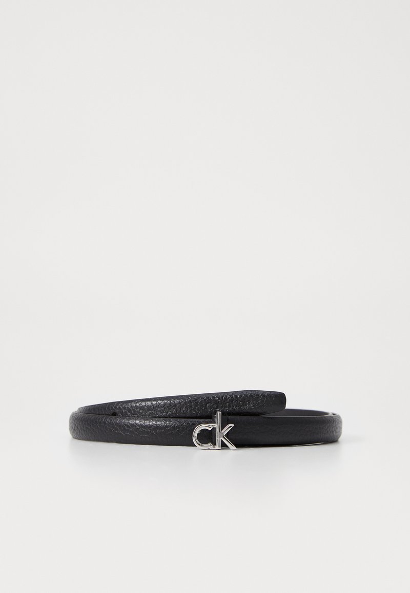 Zwarte leren riem met een textuurafwerking, voorzien van een zilveren "ck" logo accent aan de voorkant. Slank, minimalistisch ontwerp.