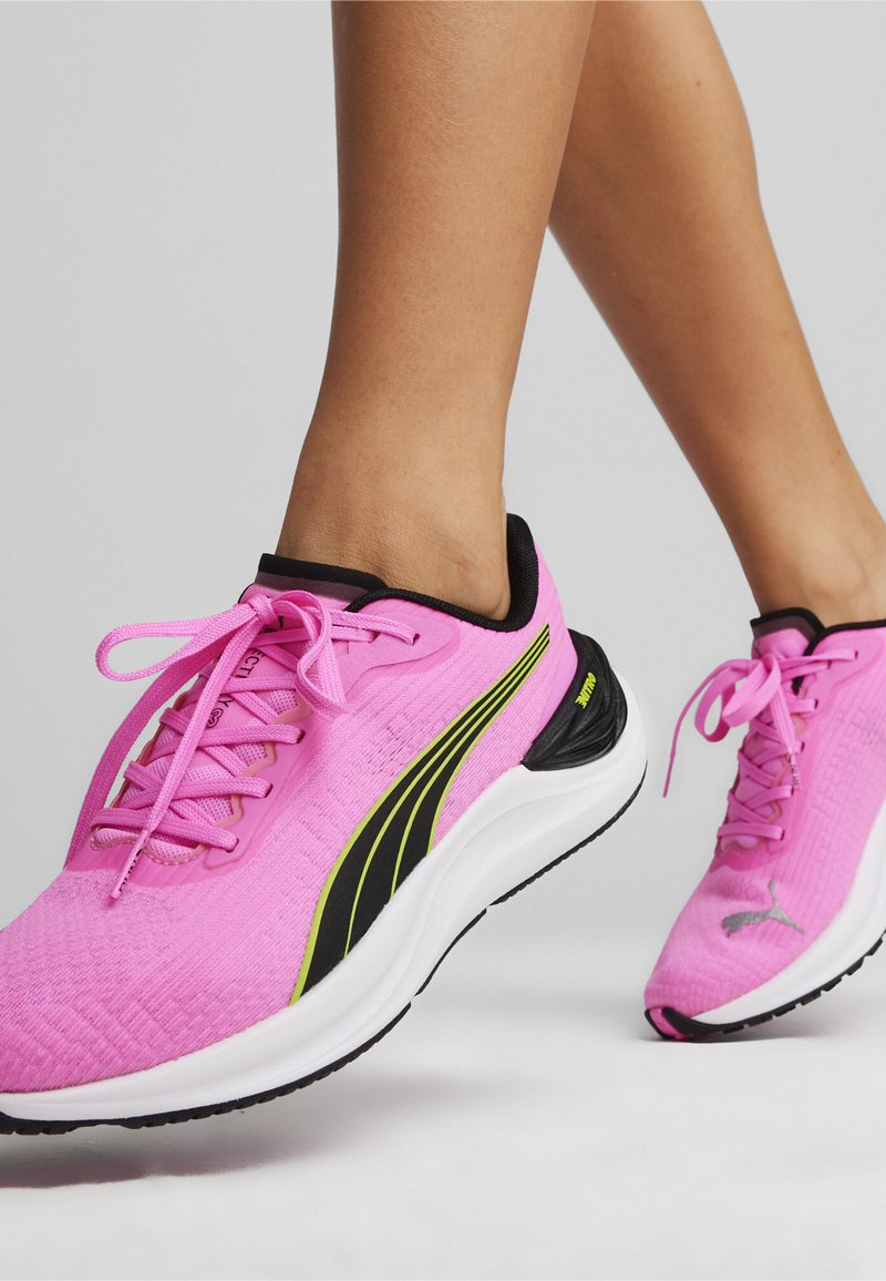 Heldere roze sport schoenen met een gestructureerde bovenkant, zwarte accenten en groene strepen. Voorzien van veters en een gevoerde zool voor comfort.