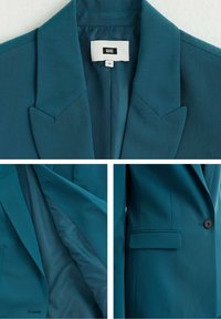 Tyrkysový blazer se strukturovanými klopami, uzávěrem na jeden knoflík a bočními kapsami. Hladká látková podšívka s kontrastním detailem.