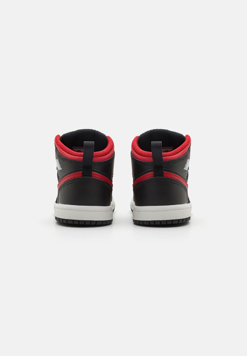 Baskets montantes avec une tige en cuir noir, des accents rouges, un col rembourré et une semelle en caoutchouc texturée. Comprend un logo à l'arrière et une boucle au talon.