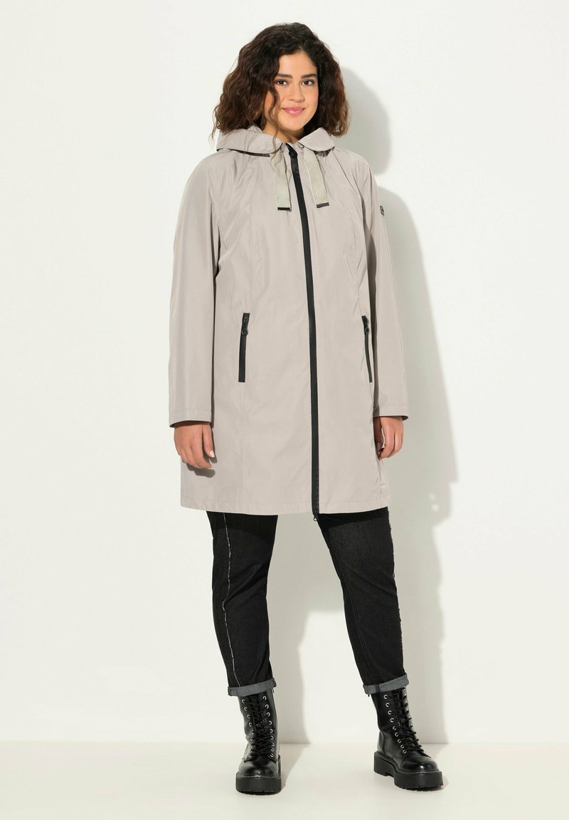 Jasnoszara wodoodporna kurtka z kapturem, z przodu na zamek błyskawiczny i dwiema bocznymi kieszeniami. Czarne akcenty przy zamku i zapięciach kieszeni.
