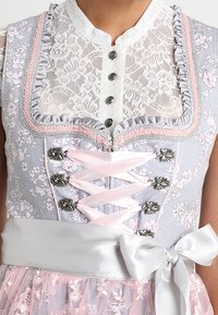 Abito floreale grigio con pizzo, scollatura arricciata, accessori in argento, lacci in raso rosa e un fiocco in vita. Presenta un sovrapposto in tulle trasparente.