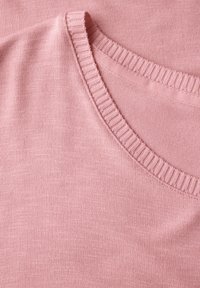 Svetle růžový pletený top s kulatým výstřihem a žebrovanými okraji, který je vyroben z hladkého a jemného materiálu.