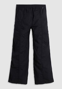 Pantalon noir à jambes larges avec taille élastique, coutures visibles et deux poches latérales sur un fond uni clair.