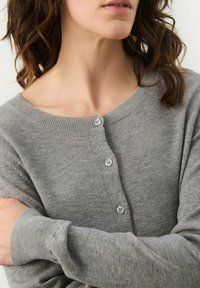 Light grey knitted cardigan featuring a boat neckline, long sleeves, and button closure at the front. Soft texture with ribbed detailing.