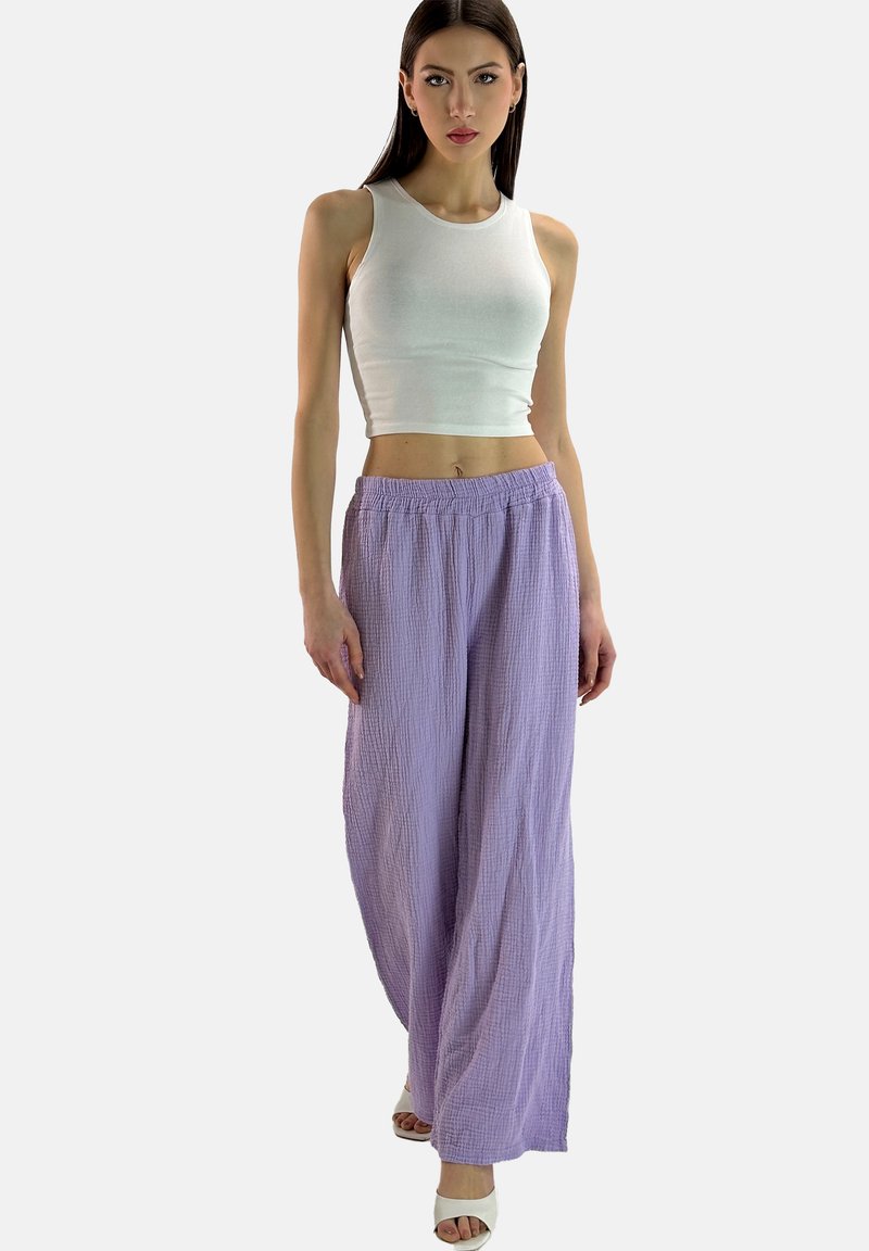 Witte mouwloze crop top gecombineerd met losse lila broek van textiel, met een elastische tailleband en een wijde pijp ontwerp.