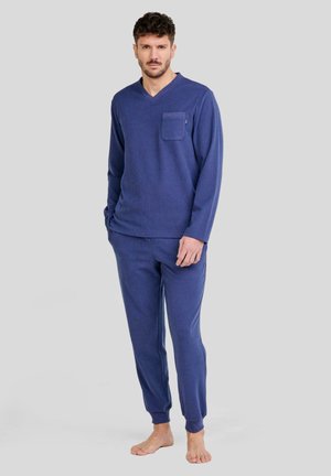 Conjunto de loungewear azul marino que incluye una camiseta de manga larga con escote en V y bolsillo en el pecho, y pantalones ajustados a juego con tobillos acampanados. Textura suave.
