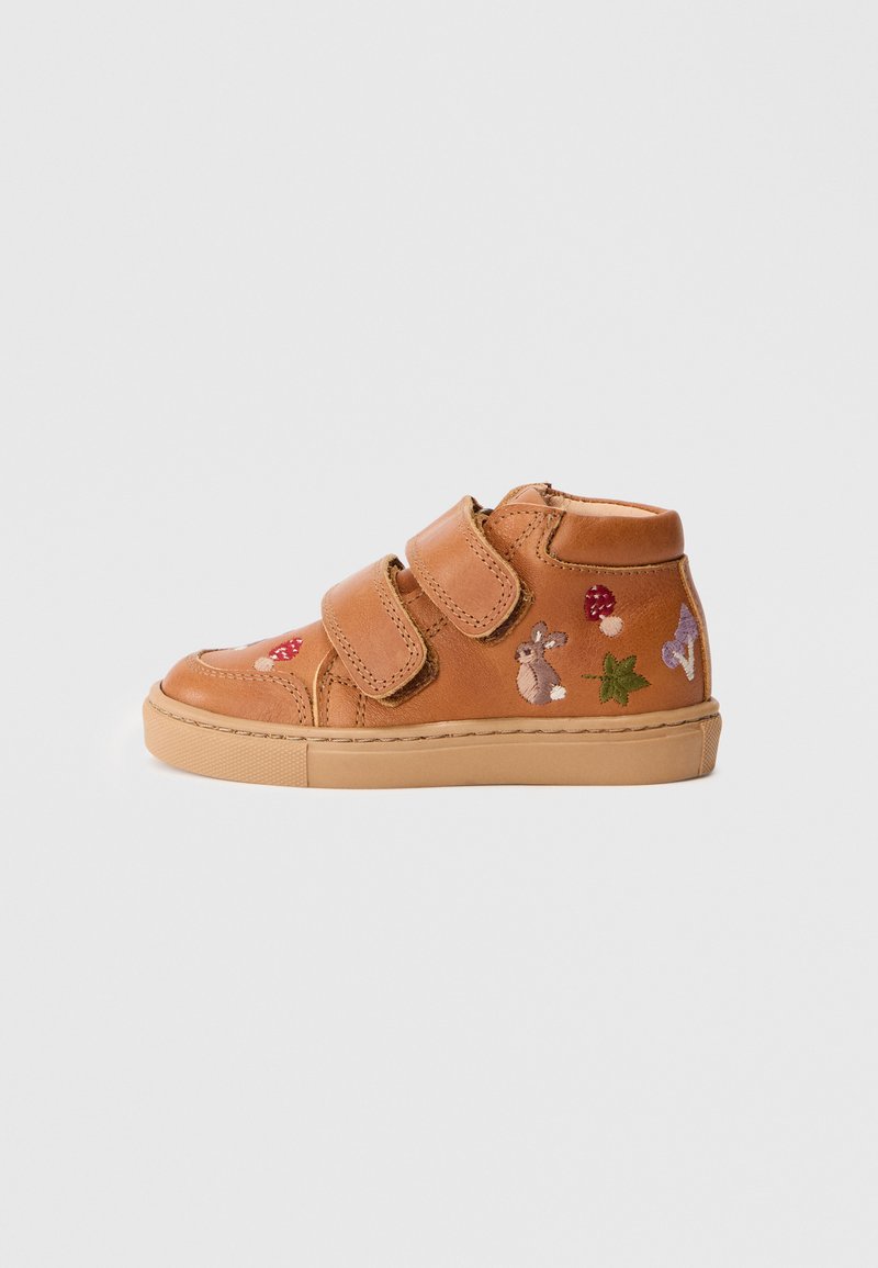 Zapato alto de cuero marrón claro con dos correas de velcro. Presenta diseños bordados de un conejo, champiñones y hojas. Suela de goma.