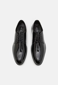 Zapatos de vestir de charol negro con un diseño elegante, puntera afilada y cinco ojetes para los cordones. El interior cuenta con un forro de marca.