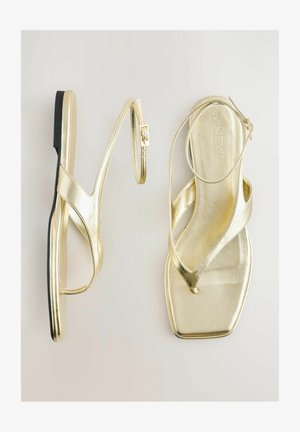 Zelta metāla sandales ar plakanu zoli, ar elegantu dizainu, krustveida siksnām un regulējamu sprādzi. Kvadrātu formas purngals.