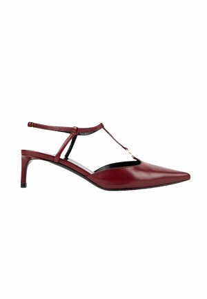Escarpin slingback en cuir rouge à bout pointu avec bride en T et accent doré sur fond blanc.