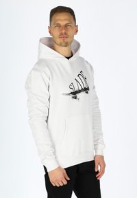 Felpa bianca con cappuccio, caratterizzata da una stampa grafica nera e una tasca frontale, realizzata in tessuto morbido con polsini e orlo a costine.