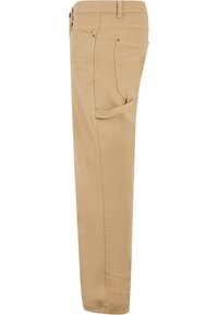 Beige chinos dengan desain kaki lurus, terbuat dari kain lembut. Fitur termasuk saku depan, saku belakang, dan detail jahitan yang halus.
