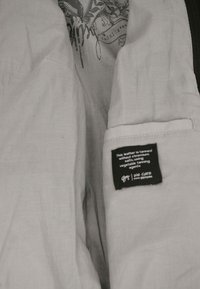 Clothing label stating leather is tanned without chromium salts using vegetable tanning agents, attached inside light-colored fabric.