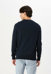 Maglione lavorato a maglia blu navy con scollatura rotonda, maniche lunghe e polsini e orlo a coste. Tessuto morbido e design aderente.