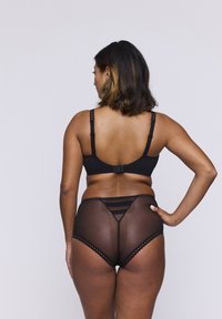 Zwart lingerie set met een zachte stof beha met verstelbare bandjes en een doorschijnende, patroon high-waisted slip met gegolfde randen.