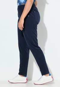 Marina blått kordfläskbyxor med resårmidja, som har sidofickor och slim fit. Matchat med vita sneakers med rosa sulor.