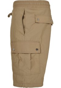 Knee-length beige cargo shorts made of lightweight material, featuring an elastic waistband, side pockets, and snap-button accents.