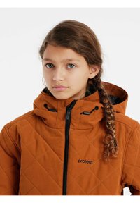 Chaqueta acolchada naranja con capucha, que cuenta con un cierre frontal y detalles en negro. El material parece suave con una superficie texturizada.