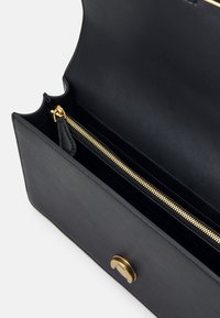 Zwarte leren handtas met een zachte textuur, voorzien van een gouden rits en hardware. Het interieur bevat een ritsvak en meerdere compartimenten.