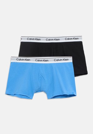 Δύο ζεύγη ανδρικά μπόξερ Calvin Klein, ένα μαύρο και ένα μπλε, με λευκές ζώνες μέσης που φέρουν το όνομα της μάρκας με μαύρο κείμενο.