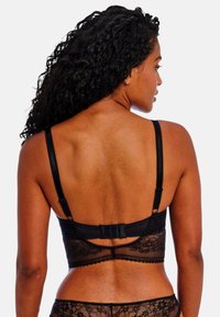 Black lace bralette featuring adjustable straps, floral pattern, hook-and-eye closure, and scalloped edges, revealing an open back design.