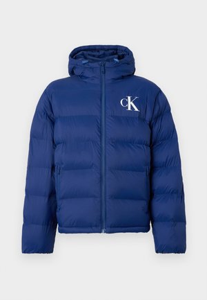 Navyblauwe gewatteerde jas met capuchon, voorrits, zijzakken en wit "cK" logo op de linkerborst.
