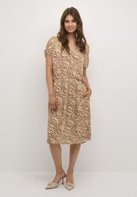 Rochie cu mâneci scurte, până la genunchi, de culoare bej, cu un model discret de zebra, talie elastică, decolteu rotund și buzunare laterale.