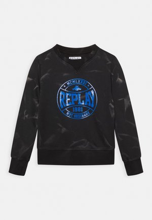 Sweat-shirt noir à manches longues avec logo circulaire bleu "REPLAY 1981 Not Ordinary" et détails blancs usés sur les manches et le corps.