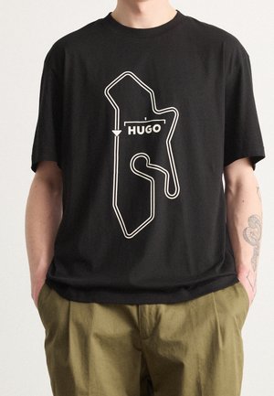 Czarny bawełniany t-shirt z białym nadrukiem przedstawiającym tor wyścigowy oraz napisem "HUGO", w luźnym kroju i okrągłym dekolcie.