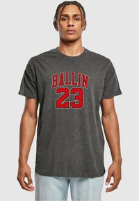 Pilkas medvilninis marškinėliai su dideliu raudonu ir baltu "BALLIN 23" grafikų priekyje. Trumpomis rankovėmis ir laisvu siluetu.